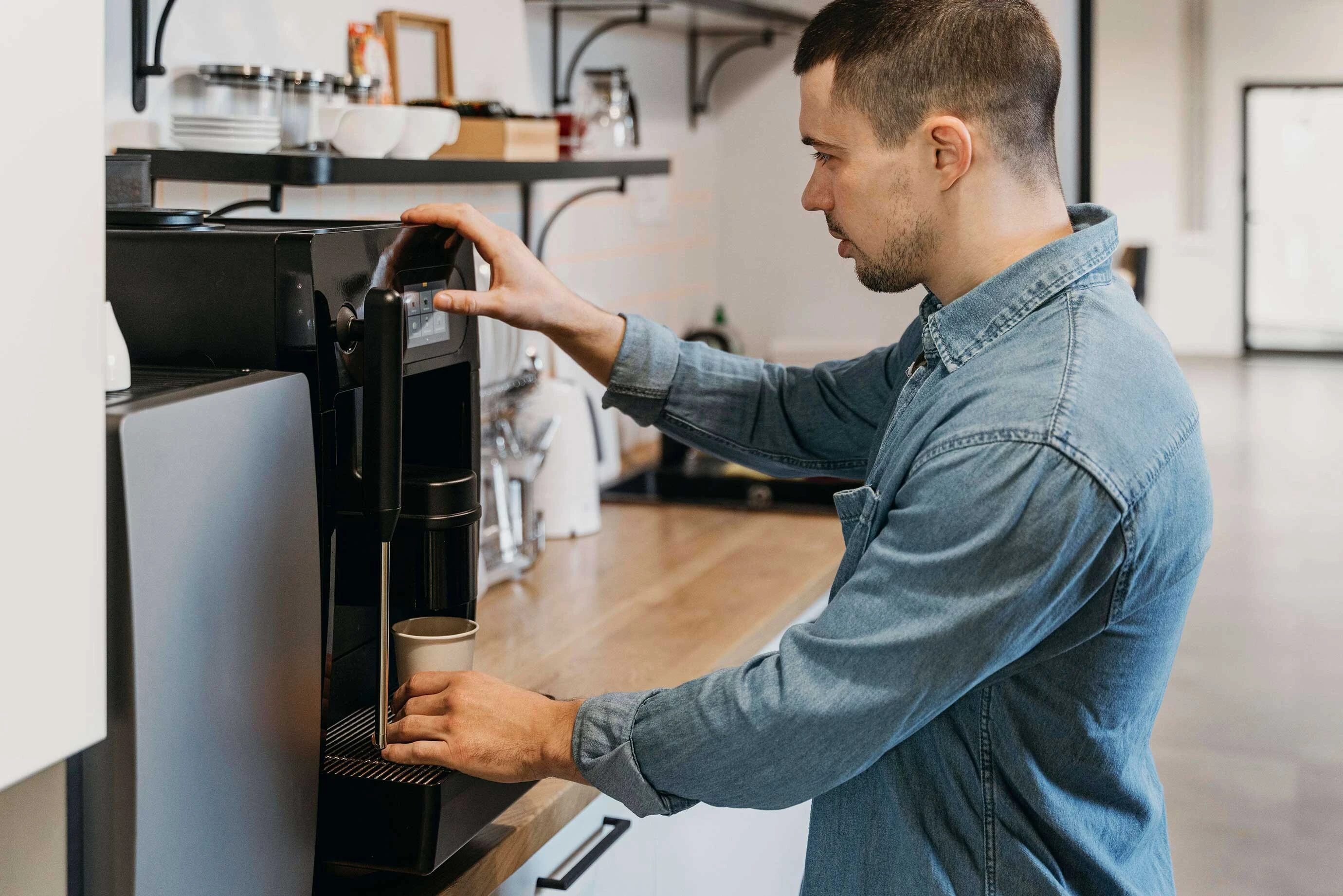 Mann an Qt-fähigem Kaffeautomat bereitet sich Kaffee zu